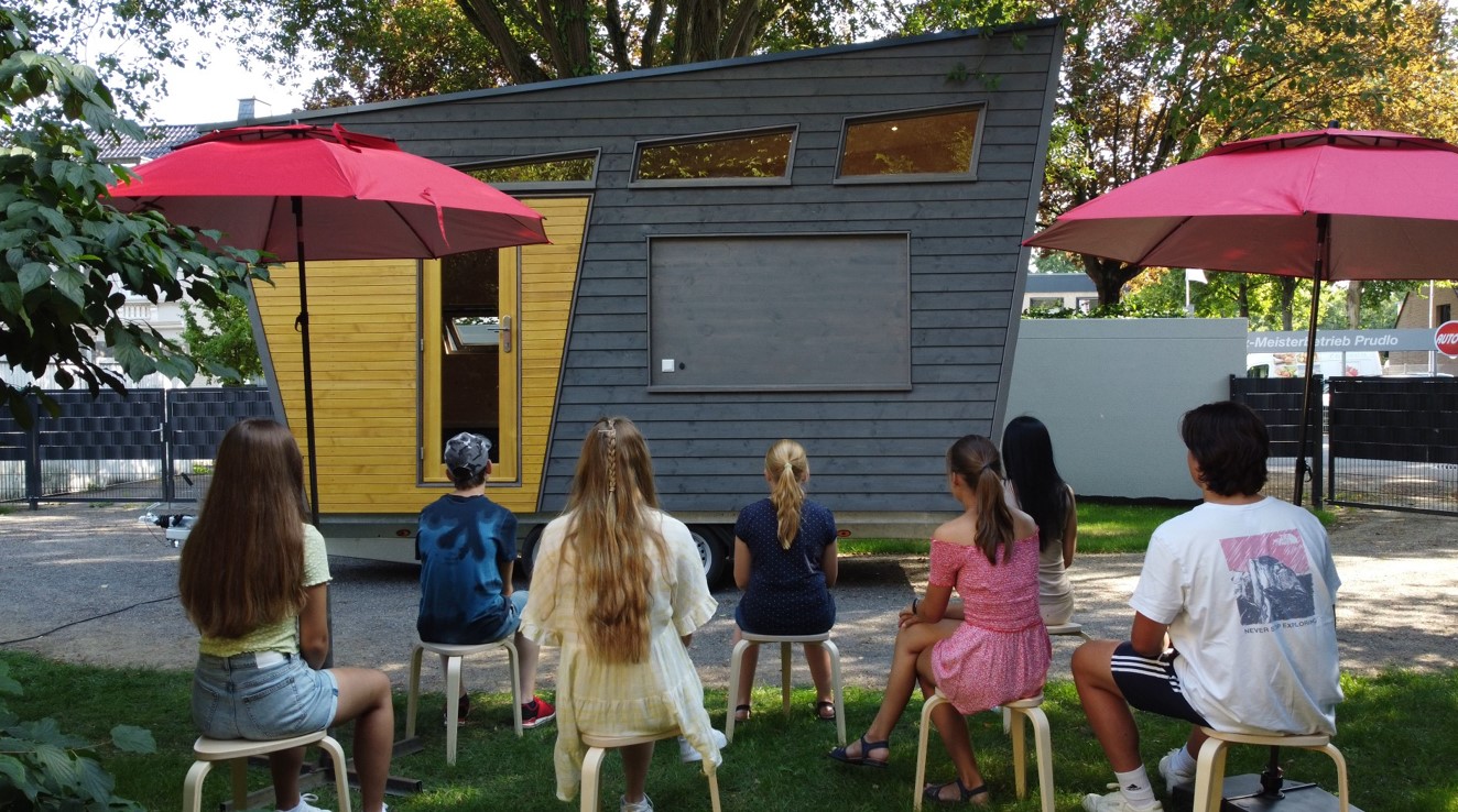 Gruppe von Jugendlichen, die vor dem Tiny Haus sitzen