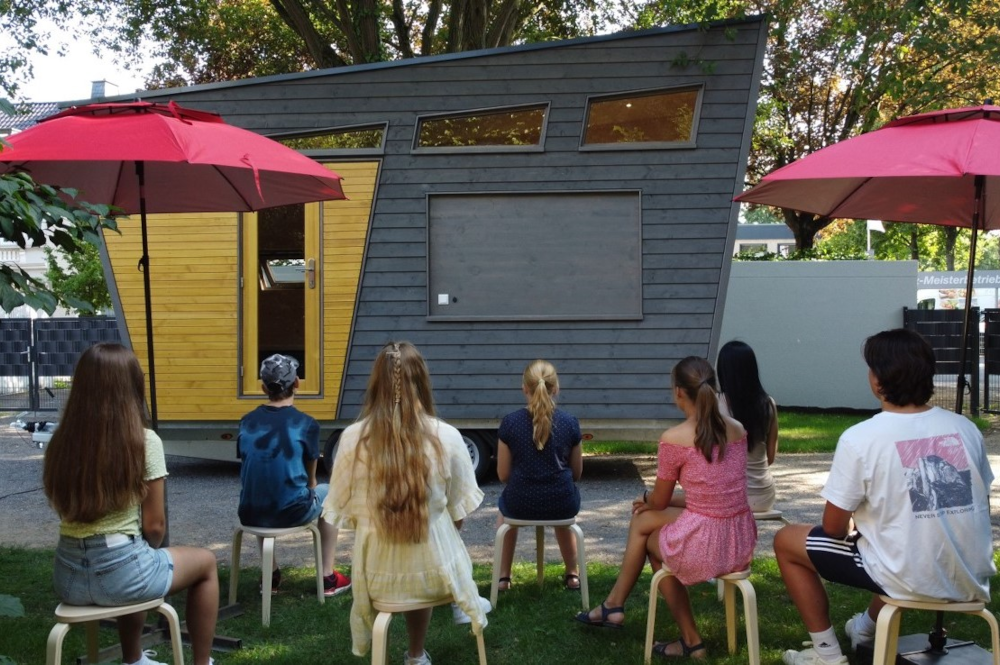 Gruppe von Jugendlichen, die vor dem Tiny Haus sitzen