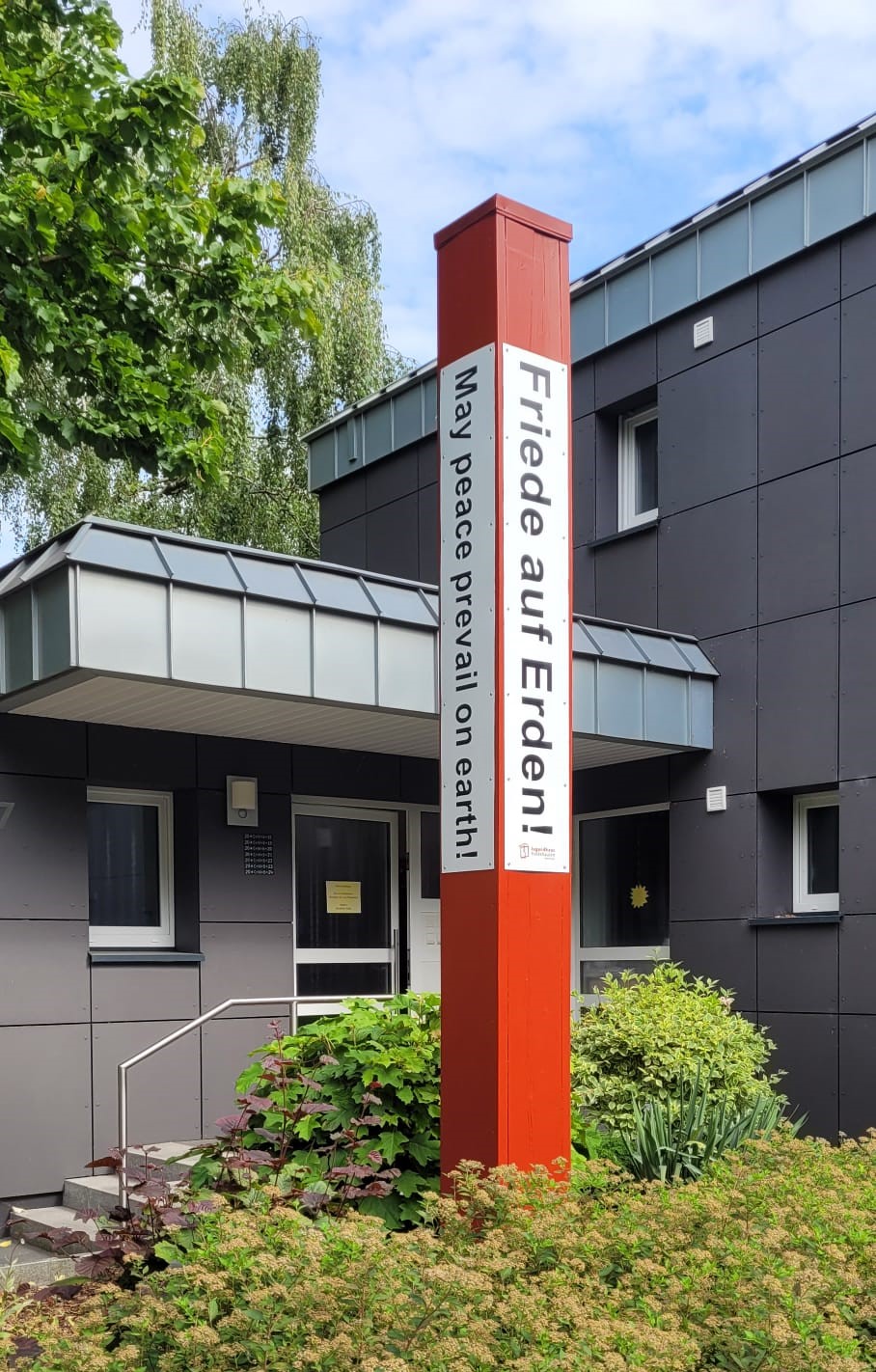 Foto Friedensmahner, der vor dem Pfarrhaus steht