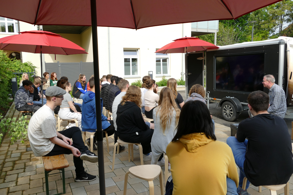 Foto von einer Gruppe von Jugendlichen, die vor dem Tiny House sitzen
